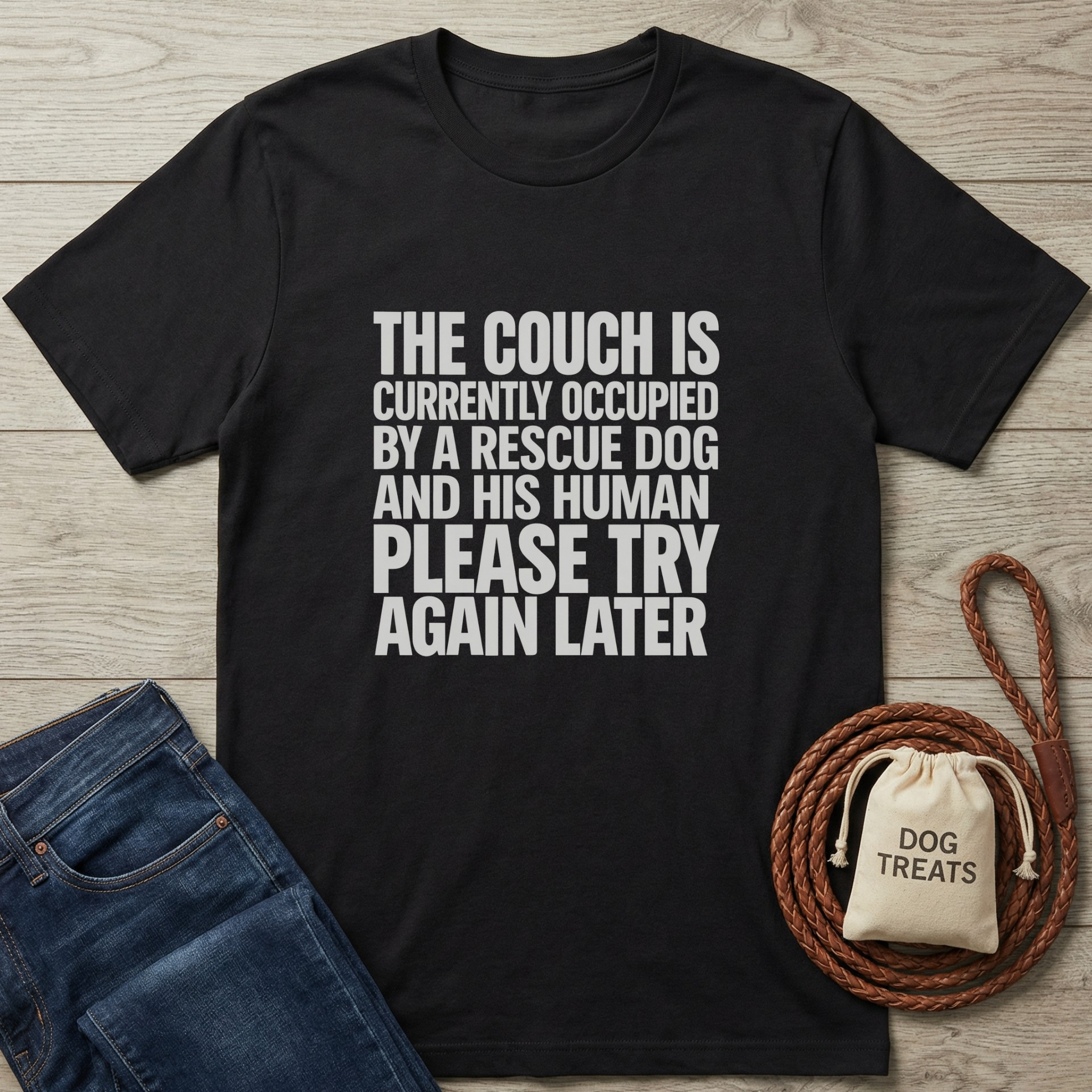 Black cotton t-shirt with "THE COUCH IS CURRENTLY OCCUPIED BY A RESCUE DOG AND HIS HUMAN PLEASE TRY AGAIN LATER" text.