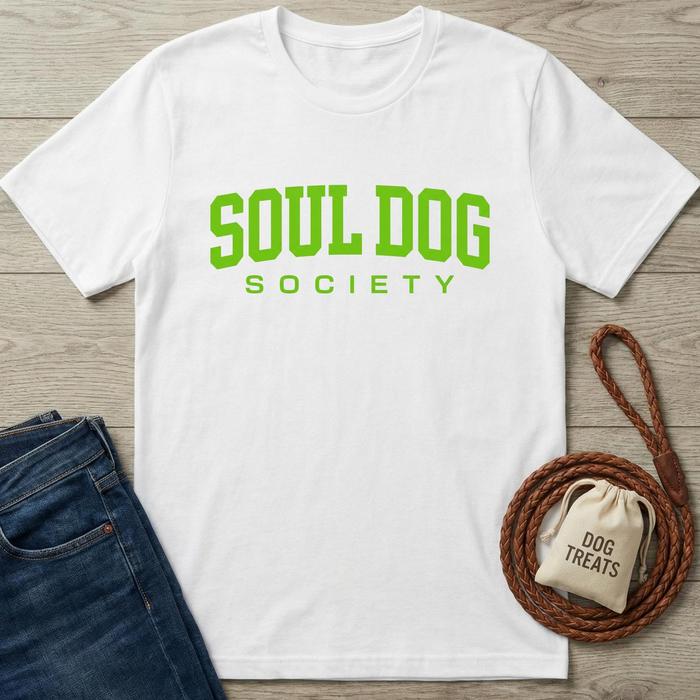 White cotton Soul Dog Society T-shirt with bright green text, next to blue jeans and dog treats.