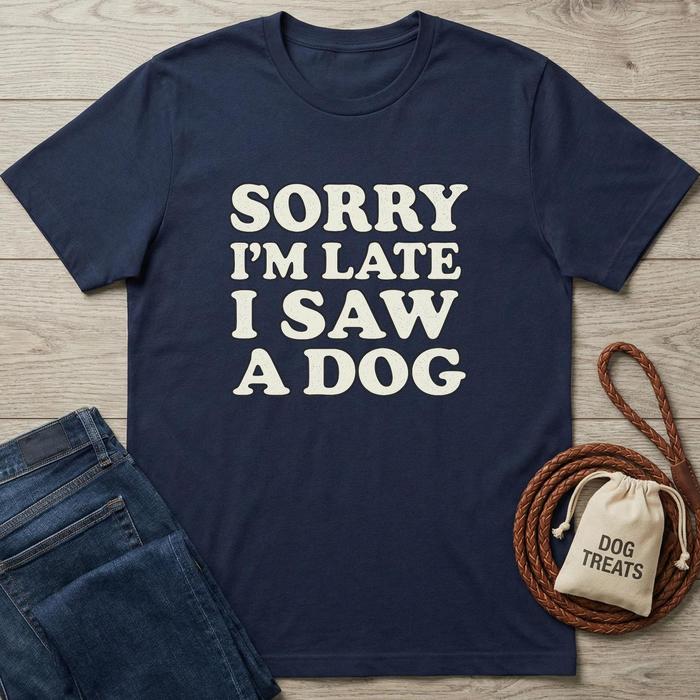 Navy blue cotton t-shirt with "SORRY I'M LATE I SAW A DOG" in cream text, next to jeans and dog treats.
