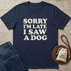Navy blue cotton t-shirt with "SORRY I'M LATE I SAW A DOG" in cream text, next to jeans and dog treats.