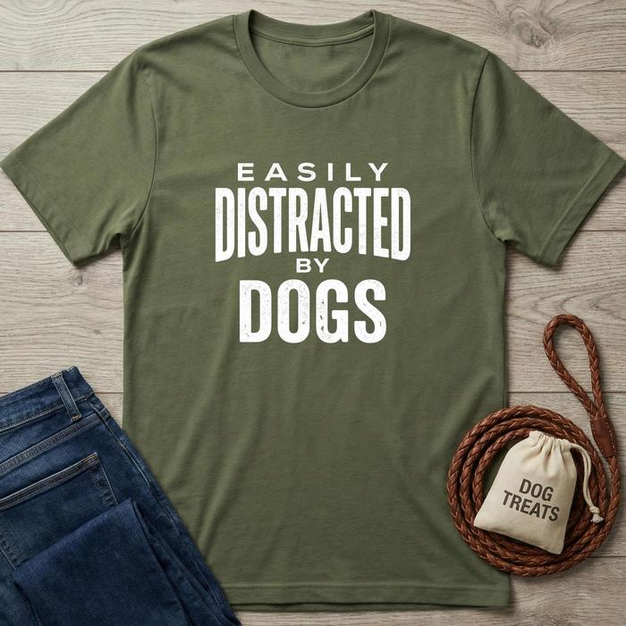Green t-shirt with 'Easily Distracted by Dogs' text, blue jeans, and dog treats bag on a wooden surface