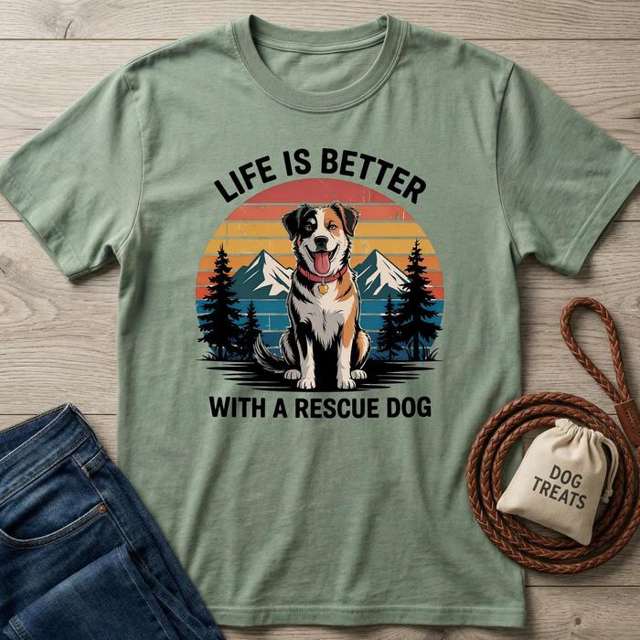 Green t-shirt with a graphic of a dog and text 'Life is better with a rescue dog' on a wooden surface.