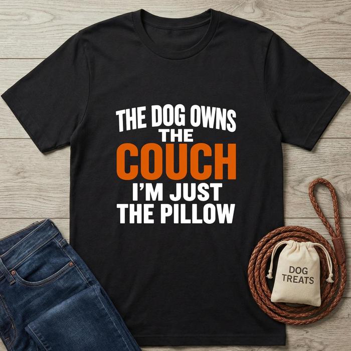 Black t-shirt with humorous text design on a wooden surface with jeans and dog treats bag.