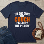 Navy blue t-shirt with humorous text on a wooden surface with jeans and a dog treat bag.