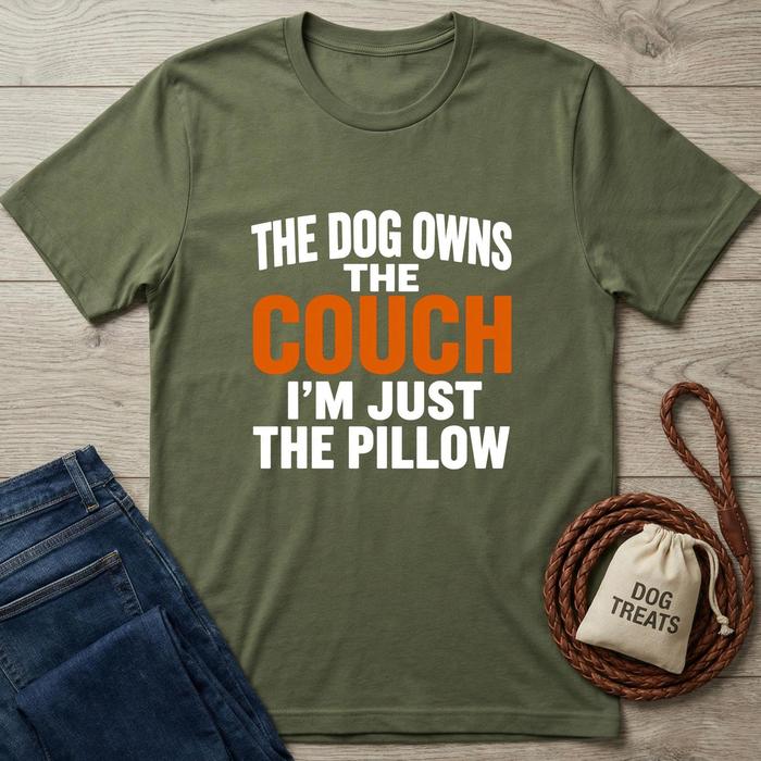 Green t-shirt with humorous text on a wooden surface with jeans and a dog treat bag.