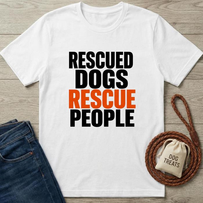 White t-shirt with 'Rescued Dogs Rescue People' text, paired with jeans and dog-related items on a wooden surface.