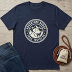 Navy blue cotton "Adventure Buddy Trail Tested K9" t-shirt with a dog and mountains design, next to jeans and dog treats.