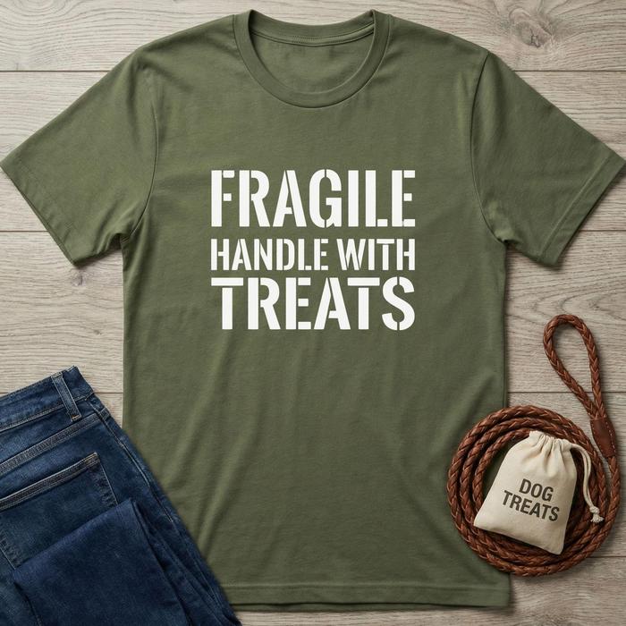 Olive green cotton t-shirt with "FRAGILE HANDLE WITH TREATS" in white text, next to jeans and dog treats bag.