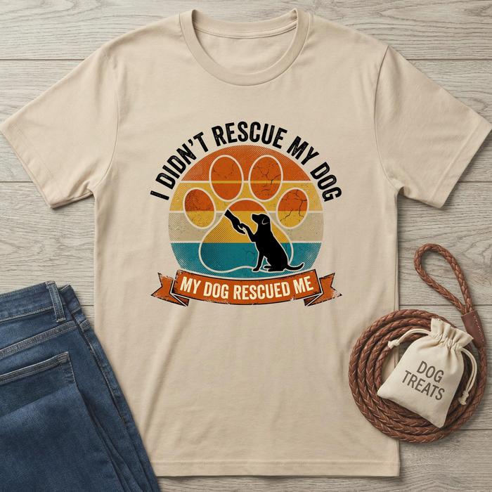 Beige cotton t-shirt with "My Dog Rescued Me" text, vintage sunset, dog silhouette, and paw print design.