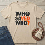 Beige cotton "Who Saved Who?" t-shirt with black and orange distressed text, next to jeans and dog treats.