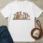 White cotton t-shirt with a colorful graphic of eight diverse dog breeds, next to jeans and dog treats.