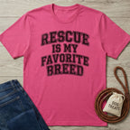 Pink Gildan Softstyle t-shirt with "Rescue Is My Favorite Breed" text, next to jeans and dog treats.