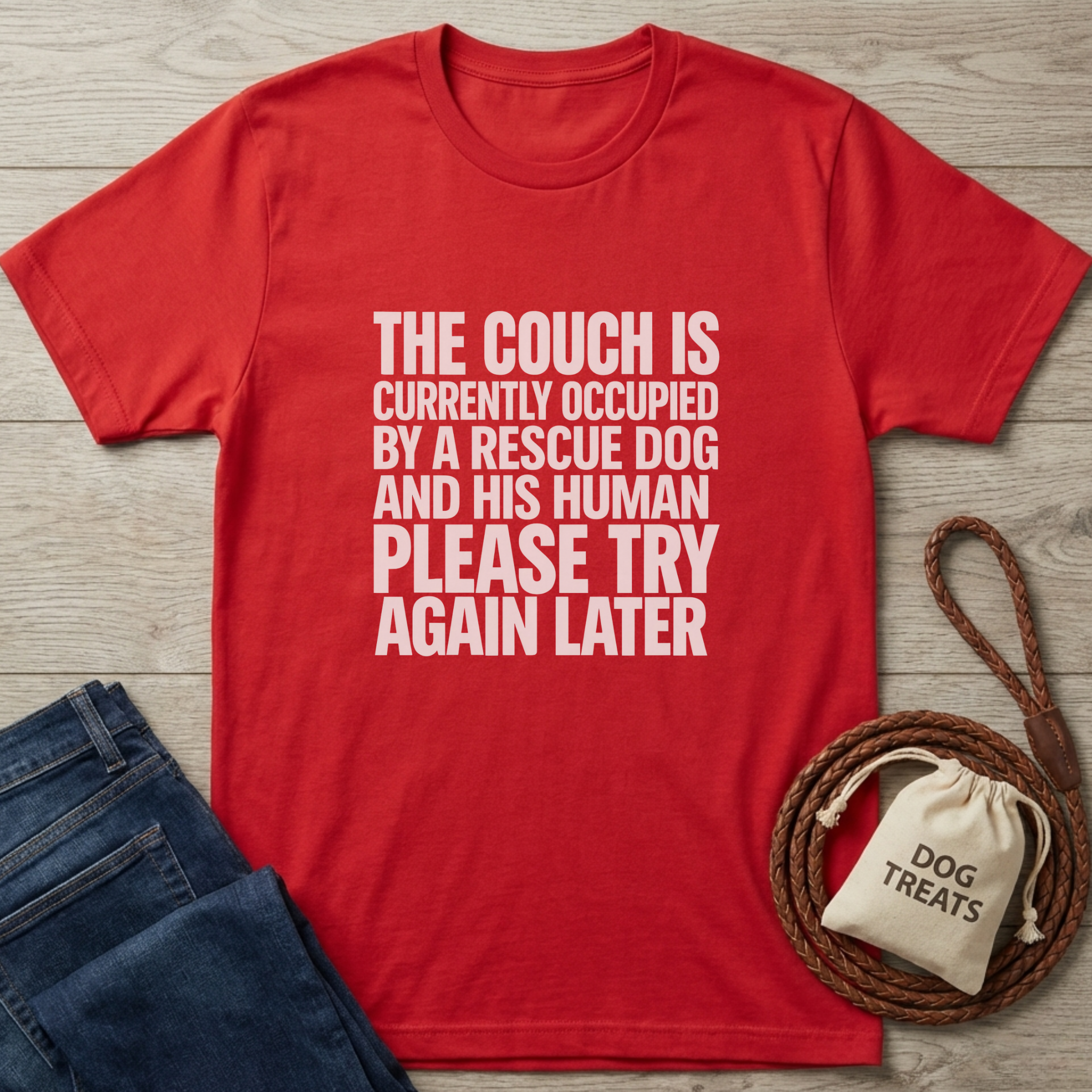 Red cotton t-shirt with "THE COUCH IS CURRENTLY OCCUPIED BY A RESCUE DOG AND HIS HUMAN PLEASE TRY AGAIN LATER" text.