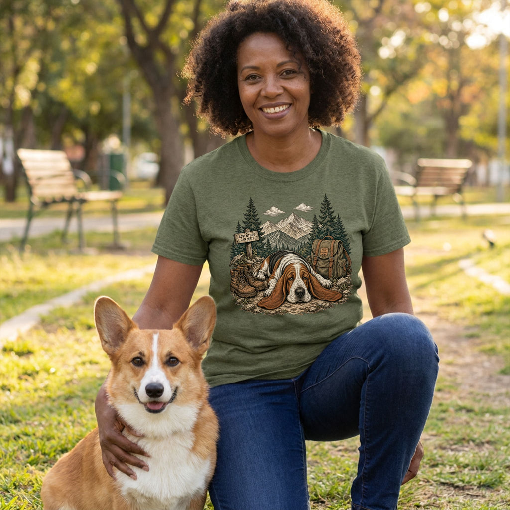 Woman wearing an olive green crewneck t-shirt featuring a graphic of a sleeping Basset Hound in a mountain forest setting.