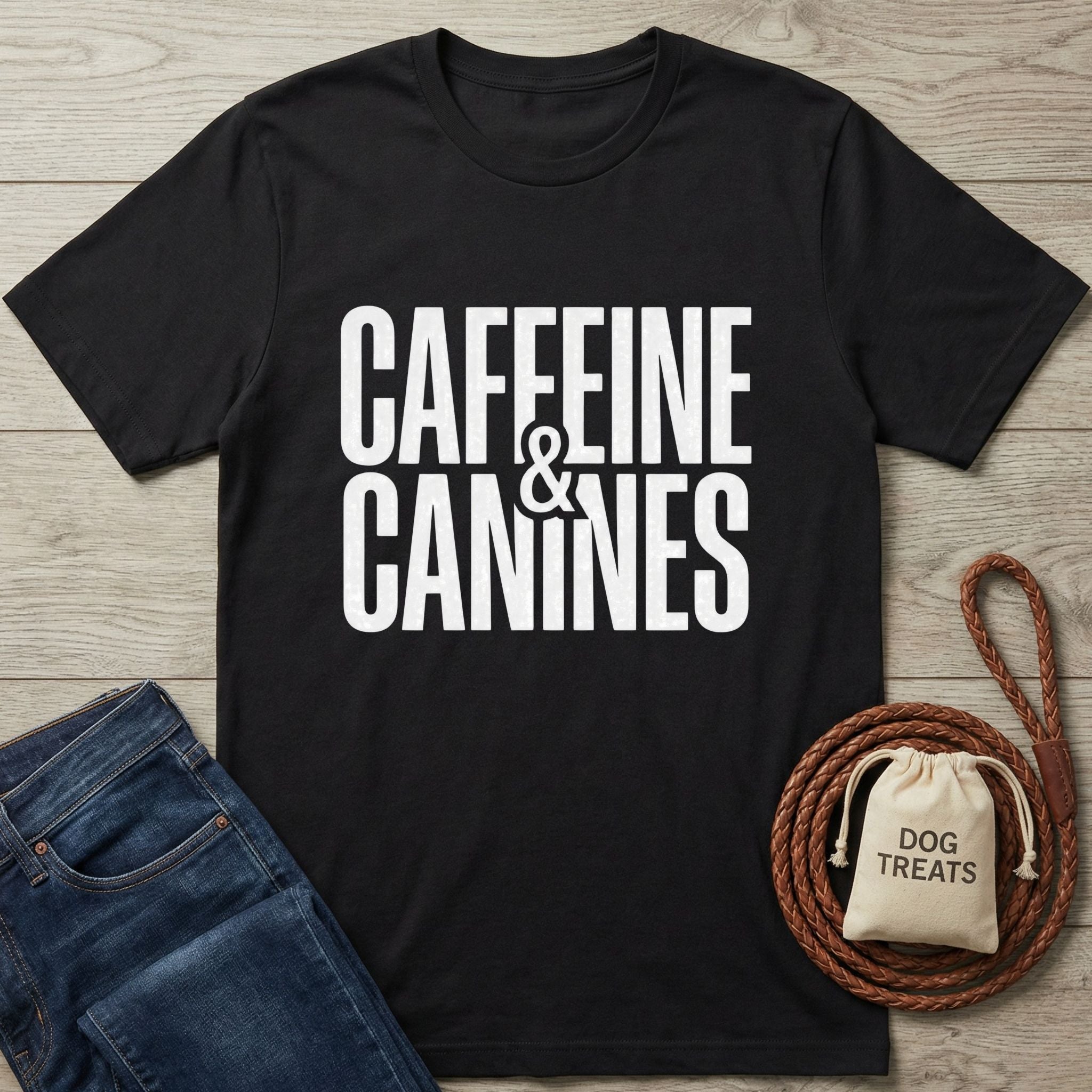 Black Gildan Softstyle t-shirt with "Caffeine & Canines" text, next to jeans, a leash, and dog treats.