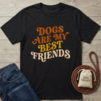 Black Gildan Softstyle t-shirt with "Dogs Are My Best Friends" in orange and yellow retro font, next to jeans and a dog leash.
