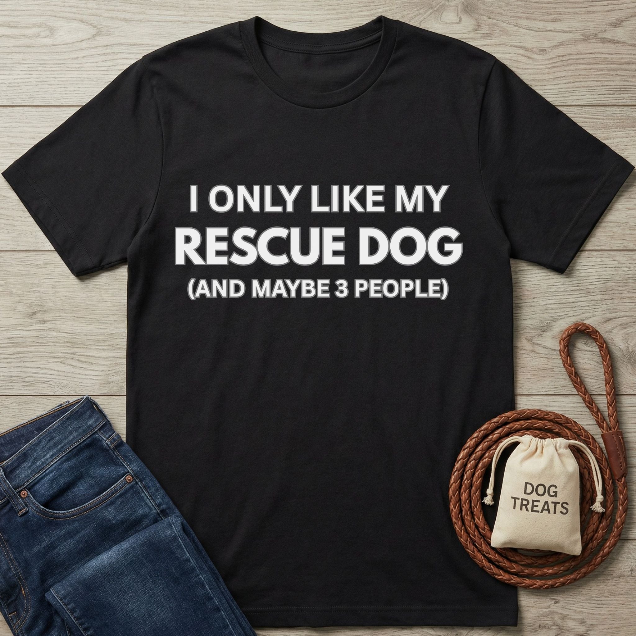Black Gildan Softstyle® 64000 tee with "I ONLY LIKE MY RESCUE DOG" text, next to jeans and dog accessories.