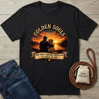 Black cotton t-shirt with "Golden Souls" sunset graphic of a person and senior dog by a lake.
