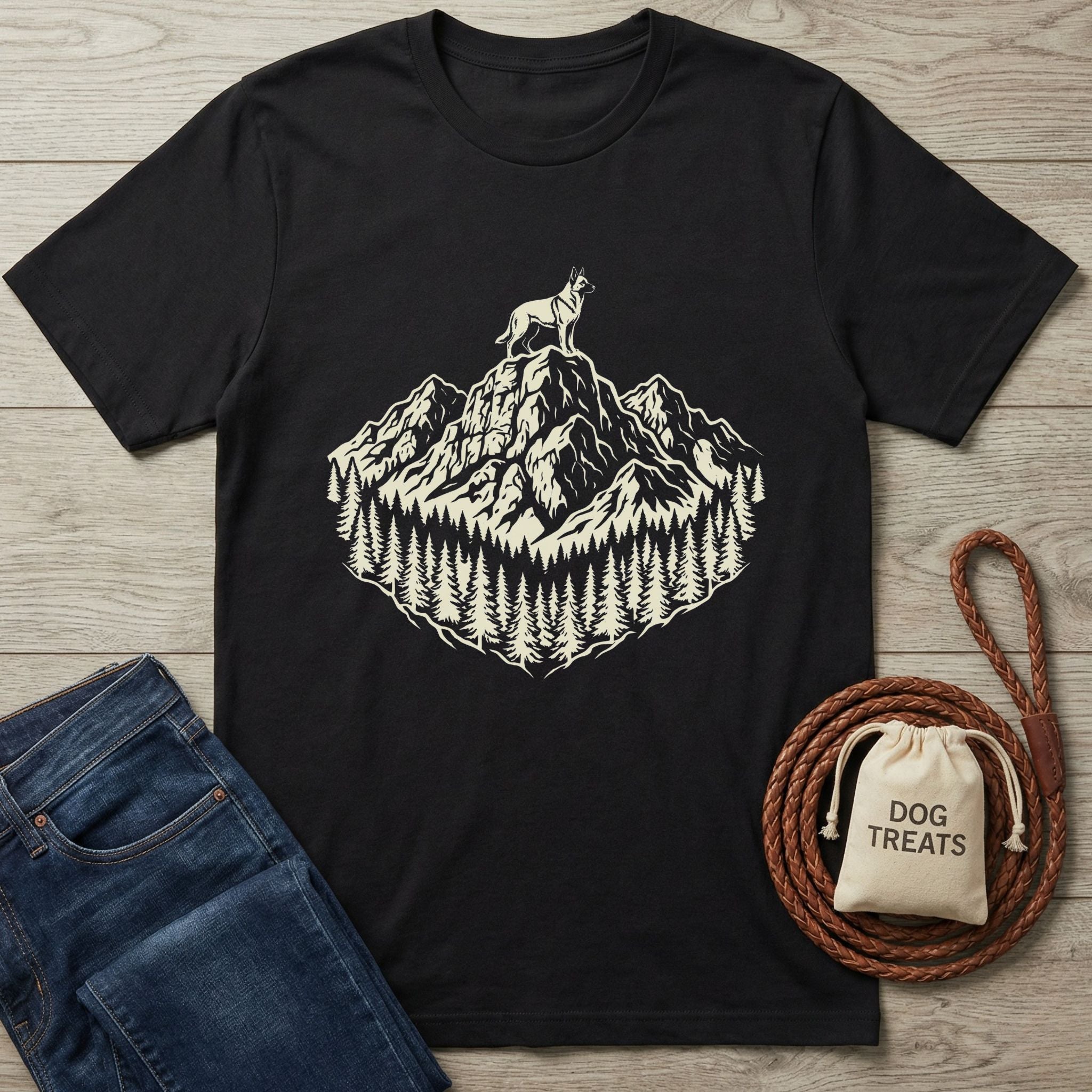 Black cotton t-shirt with a cream graphic of a dog on a mountain peak surrounded by pine trees.