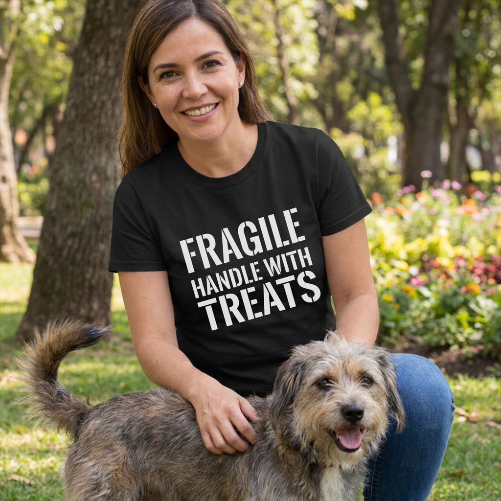 Woman in a black "FRAGILE HANDLE WITH TREATS" Gildan Softstyle® T-shirt petting a dog outdoors.