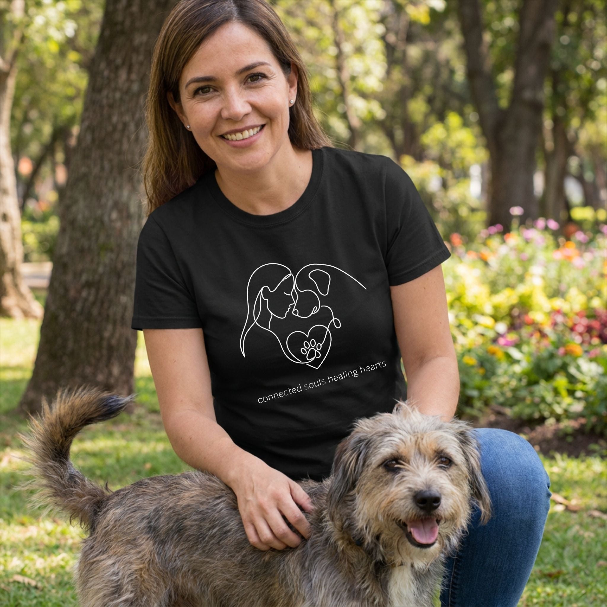 Woman in black "Connected Souls" tee with white line art design, petting a rescue dog outdoors.