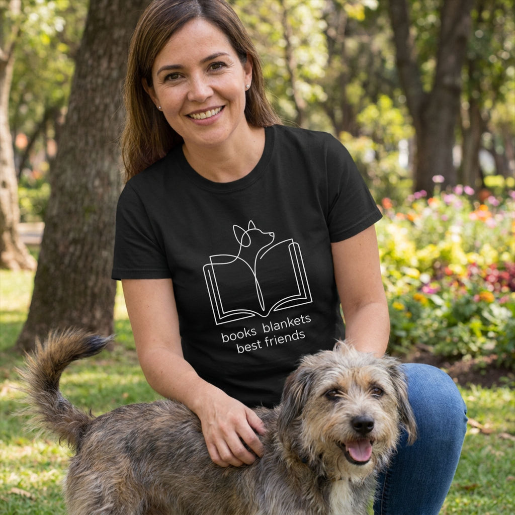 Woman in black "Books Blankets Best Friends" tee with dog outline, petting a scruffy dog outdoors.