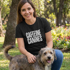 Woman in black "Caffeine & Canines" tee petting a scruffy dog in a park.