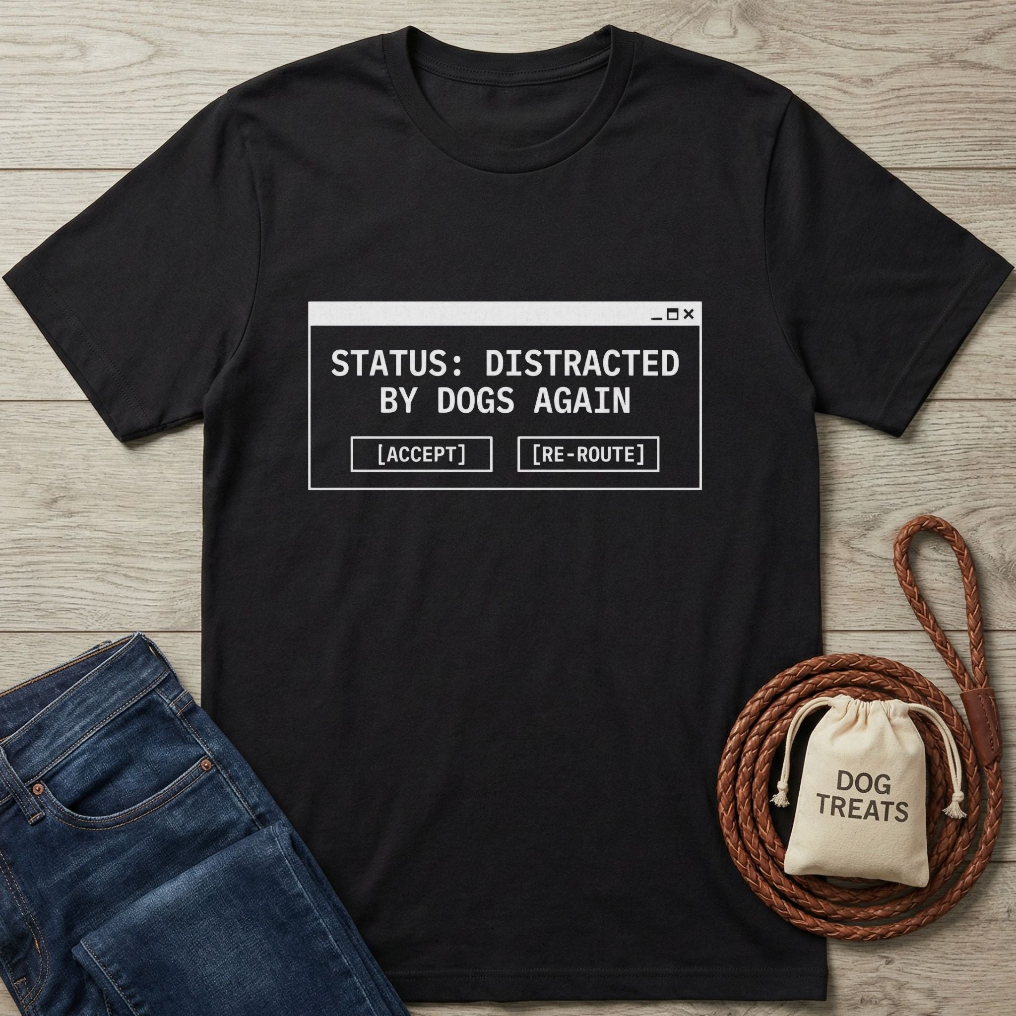 Black Gildan Softstyle® cotton tee with "STATUS: DISTRACTED BY DOGS AGAIN" graphic, next to jeans and dog treats.