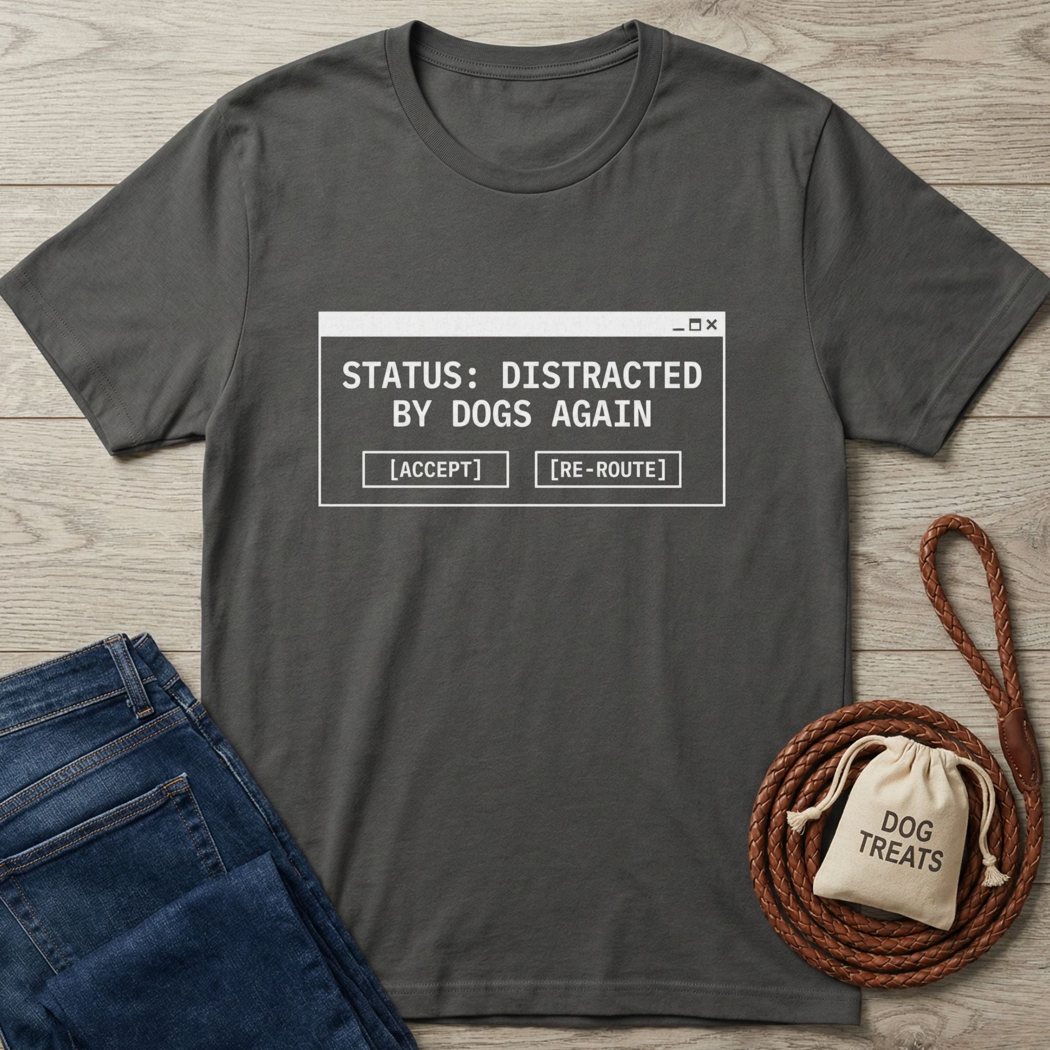 Dark grey Gildan Softstyle t-shirt with "STATUS: DISTRACTED BY DOGS AGAIN" graphic, next to jeans and dog treats.