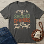 Dark grey Gildan Softstyle t-shirt with "Powered By Second Chances and Tail Wags" design, next to jeans and dog treats.