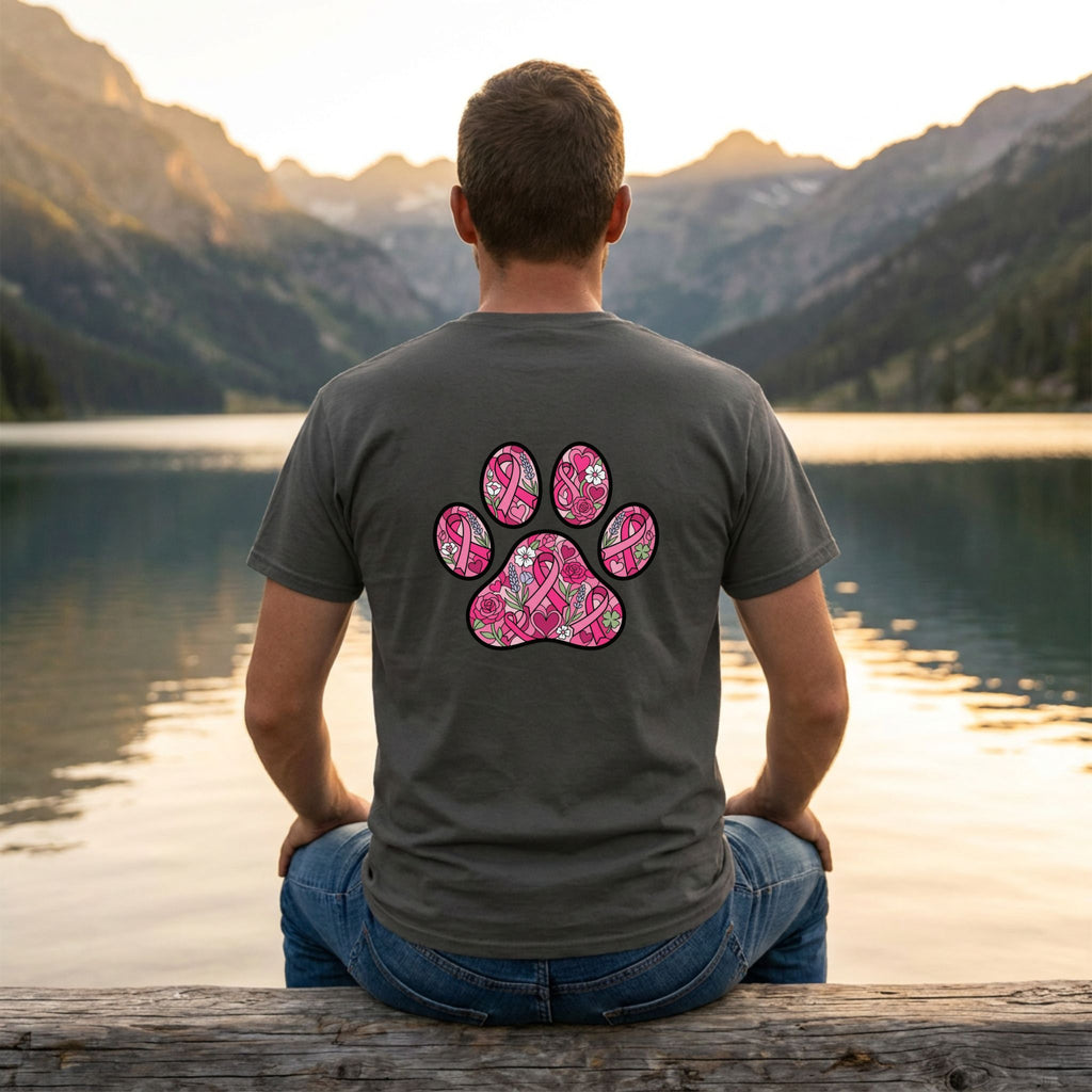 Man in a charcoal Gildan Softstyle tee with a large pink floral paw print design on the back, sitting by a lake.