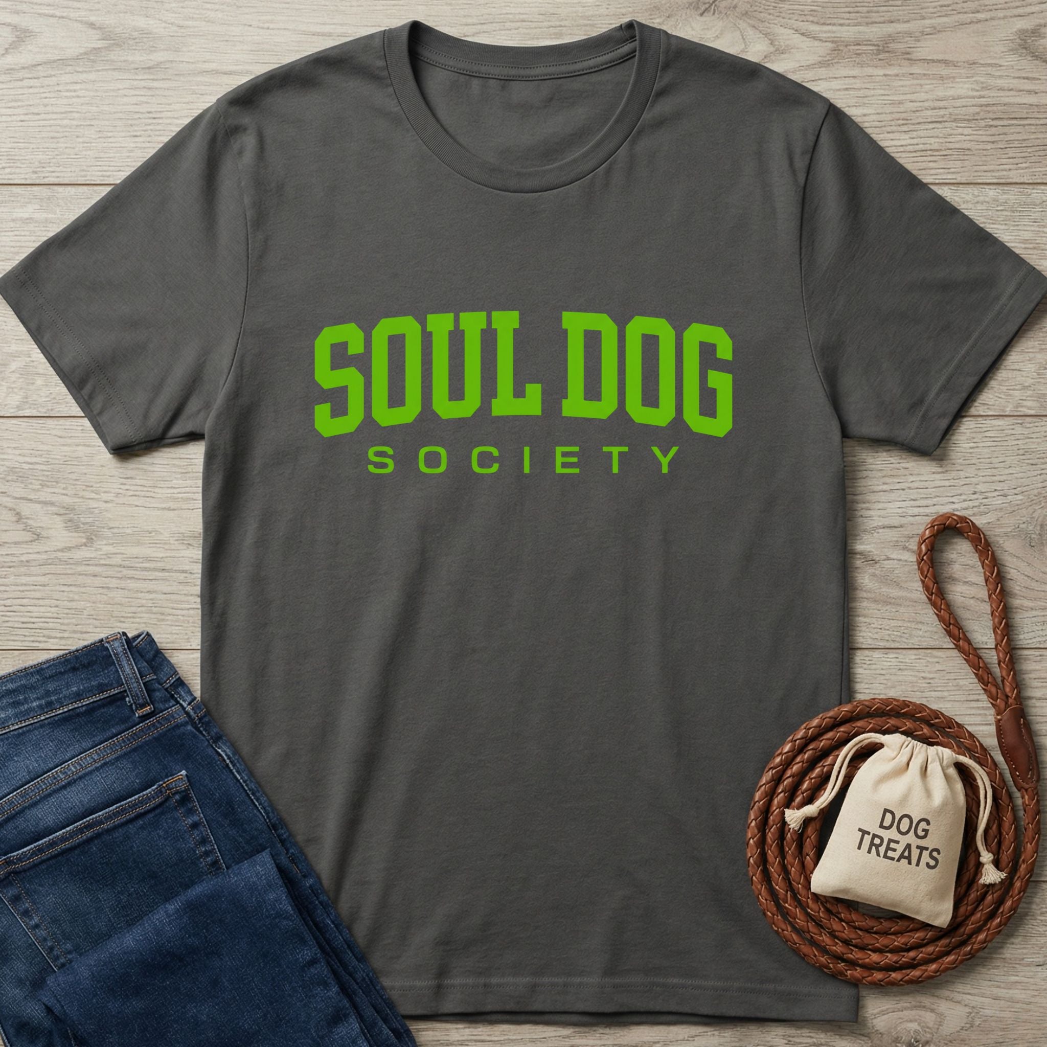 Charcoal grey Gildan Softstyle t-shirt with "SOUL DOG SOCIETY" in bright green, next to jeans and dog treats.