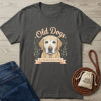 Charcoal grey "Old Dogs Best Dogs" t-shirt with a yellow lab graphic, jeans, and dog treats bag.