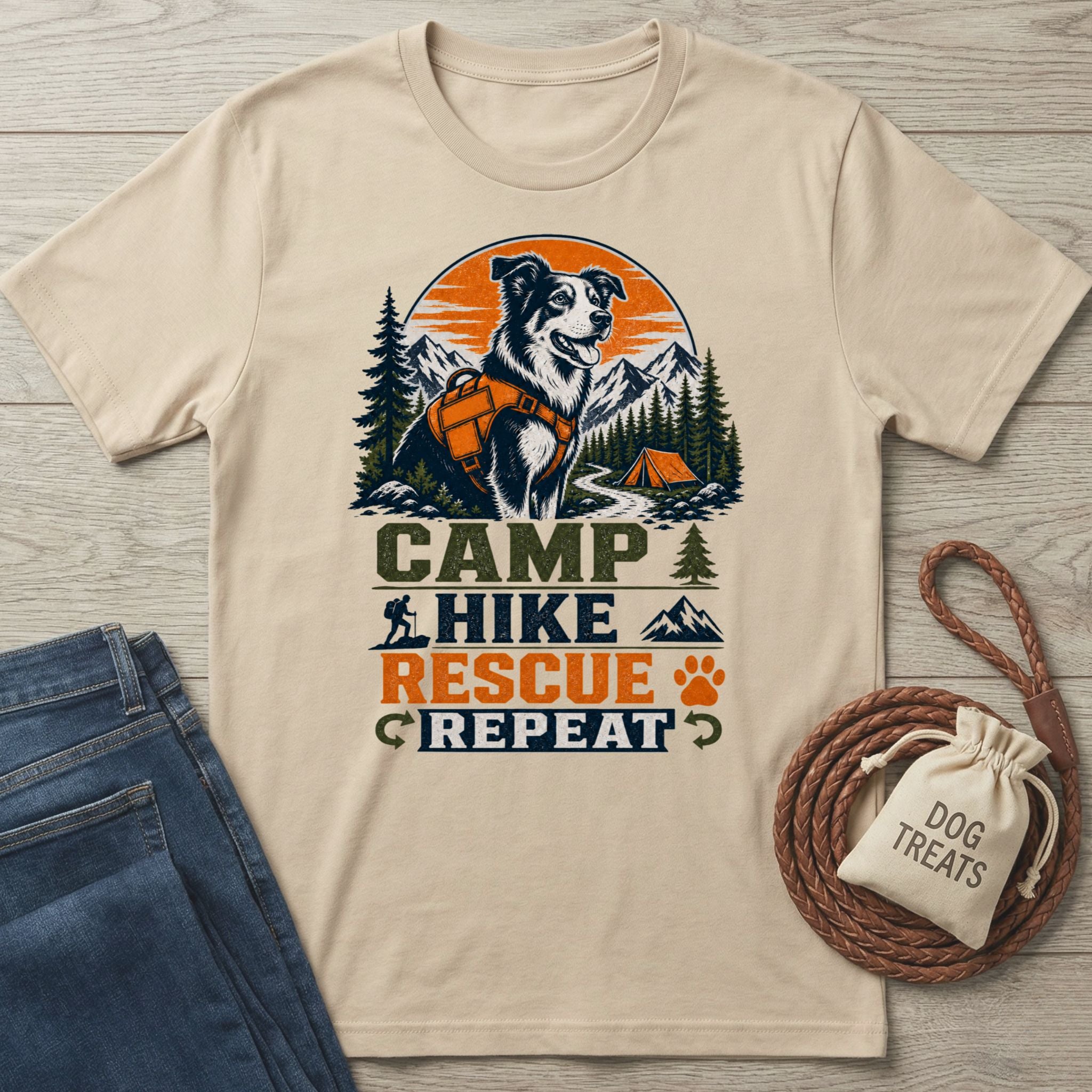 Beige crewneck t-shirt featuring a graphic of a dog in a hiking harness with mountains, a tent, and Camp Hike Rescue Repeat text.