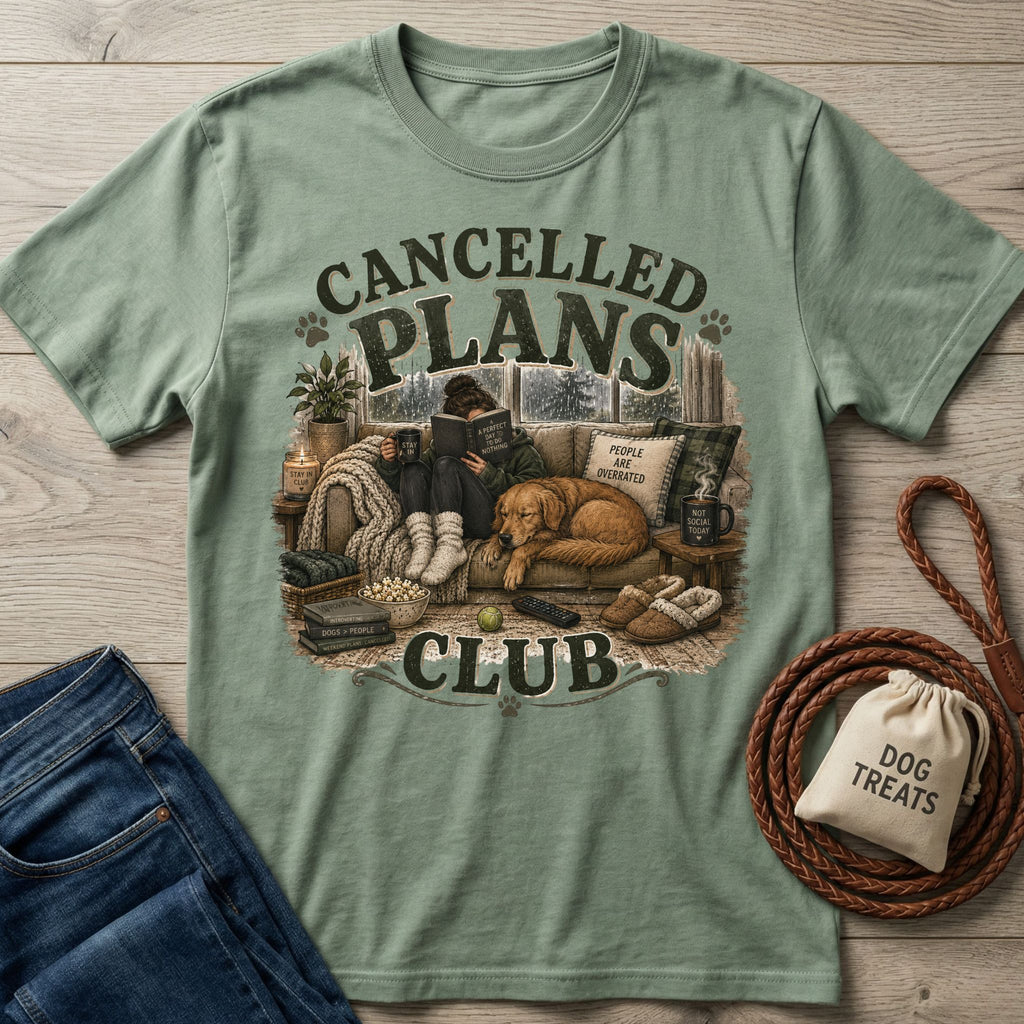 Sage green crewneck t-shirt featuring a cozy graphic of a person reading with a dog on a couch, with Cancelled Plans Club text.