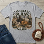 Grey crewneck t-shirt featuring a graphic of a person reading on a couch with a dog, text reads Cancelled Plans Club.