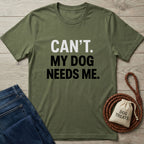 Olive green "Can't. My Dog Needs Me." t-shirt with jeans, leash, and treat bag.