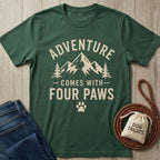 Forest green "Adventure Comes With Four Paws" T-shirt with mountain and tree graphic, beside jeans and dog treats.