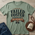 Sage green "Official Failed Foster Success Story No Regrets" t-shirt with a dog paw print design, next to jeans and dog treats.
