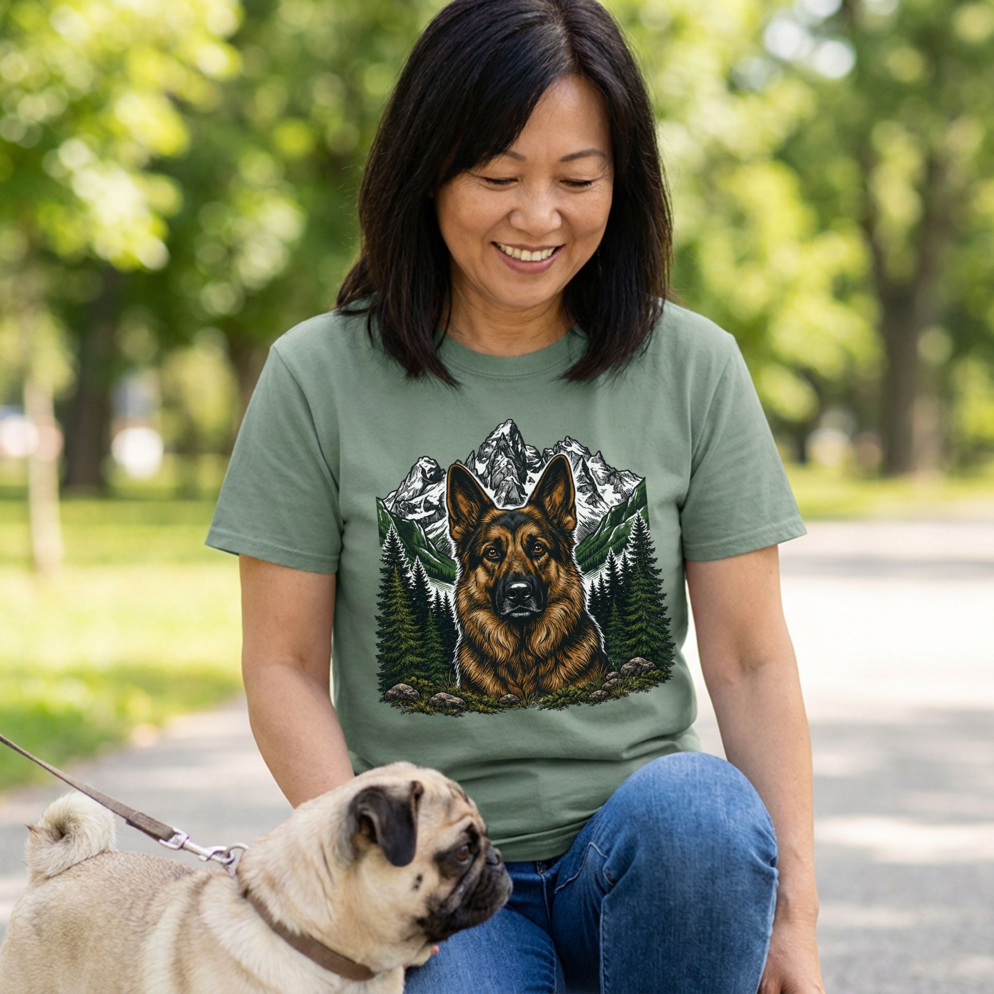 Woman wearing a sage green crewneck t-shirt featuring a German Shepherd portrait with a mountain and pine forest graphic.