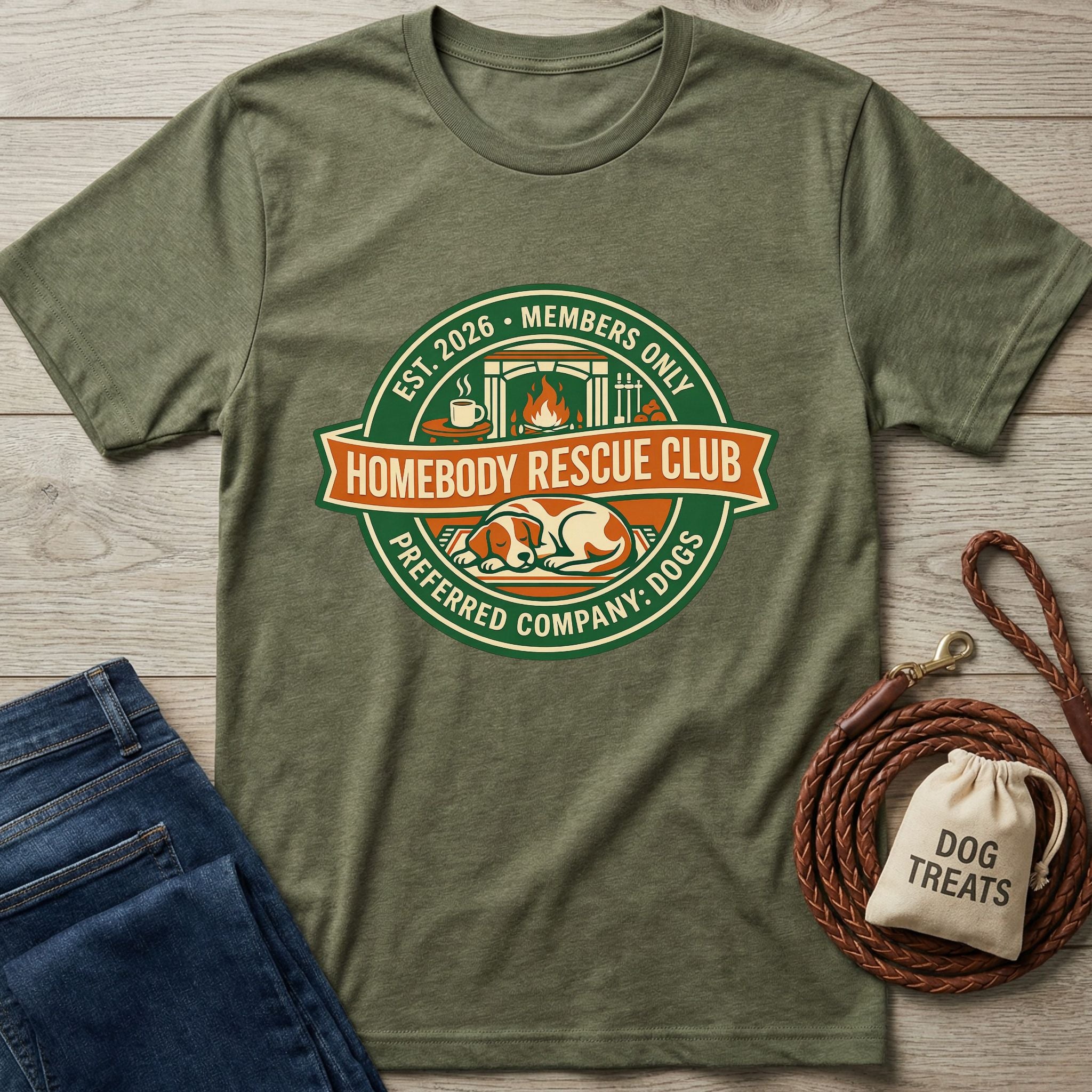 Olive green Homebody Rescue Club t-shirt with a sleeping dog graphic, next to jeans, a leash, and dog treats.