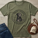 Olive green "Trust Issues Society" t-shirt with a black dog graphic, laid flat with jeans and dog treats.