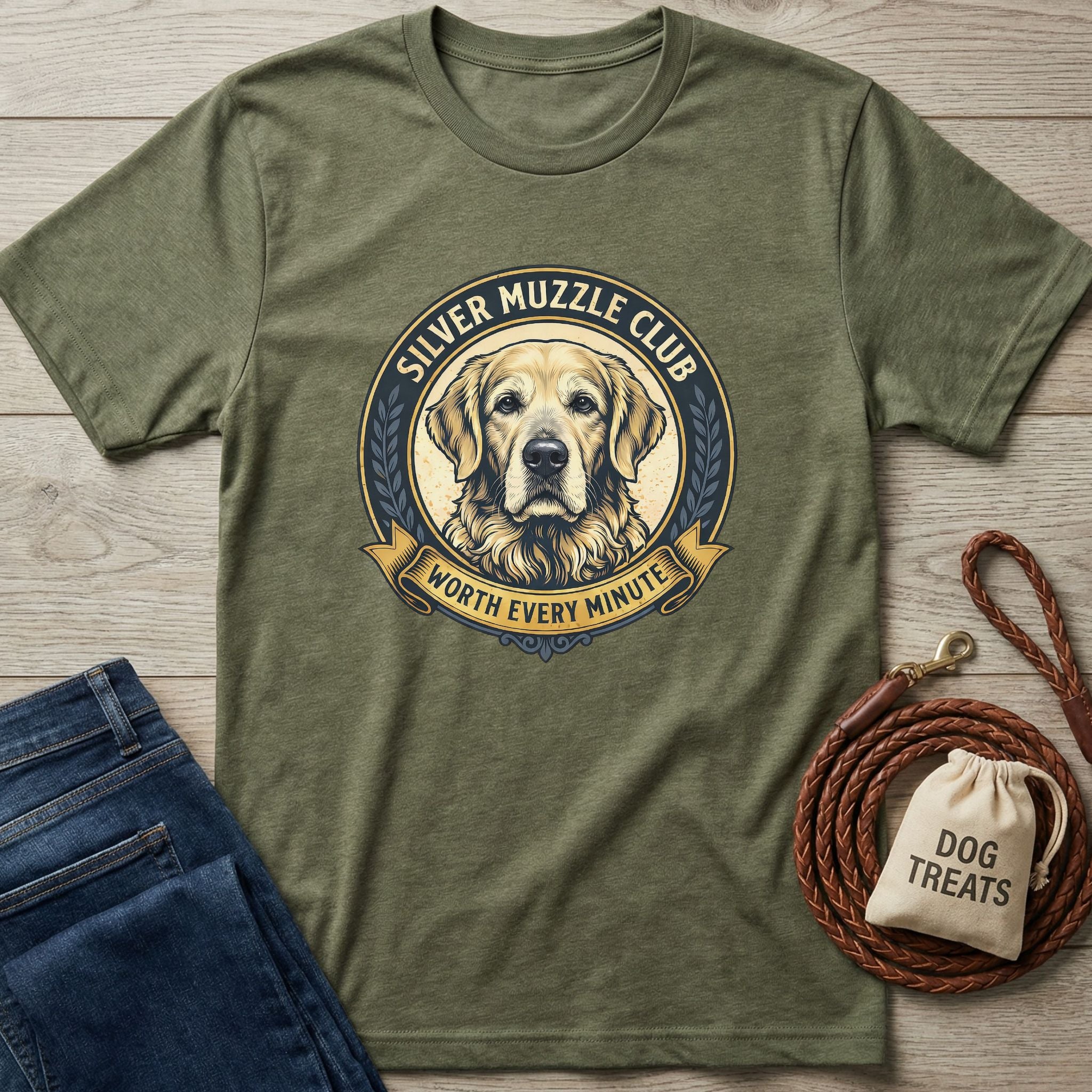Olive green Silver Muzzle Club t-shirt with a Golden Retriever graphic, next to jeans, a leash, and dog treats.