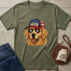 Green t-shirt with a dog graphic wearing an American flag cap, next to jeans and a dog leash on a wooden surface.