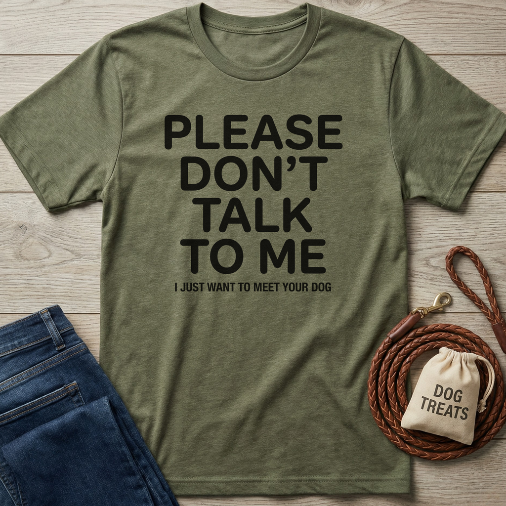 Olive green "Please Don't Talk To Me" t-shirt with black text, folded jeans, and dog accessories.