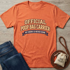 Orange Gildan Softstyle® t-shirt with "Official Poop Bag Carrier" text, next to jeans and dog treats.
