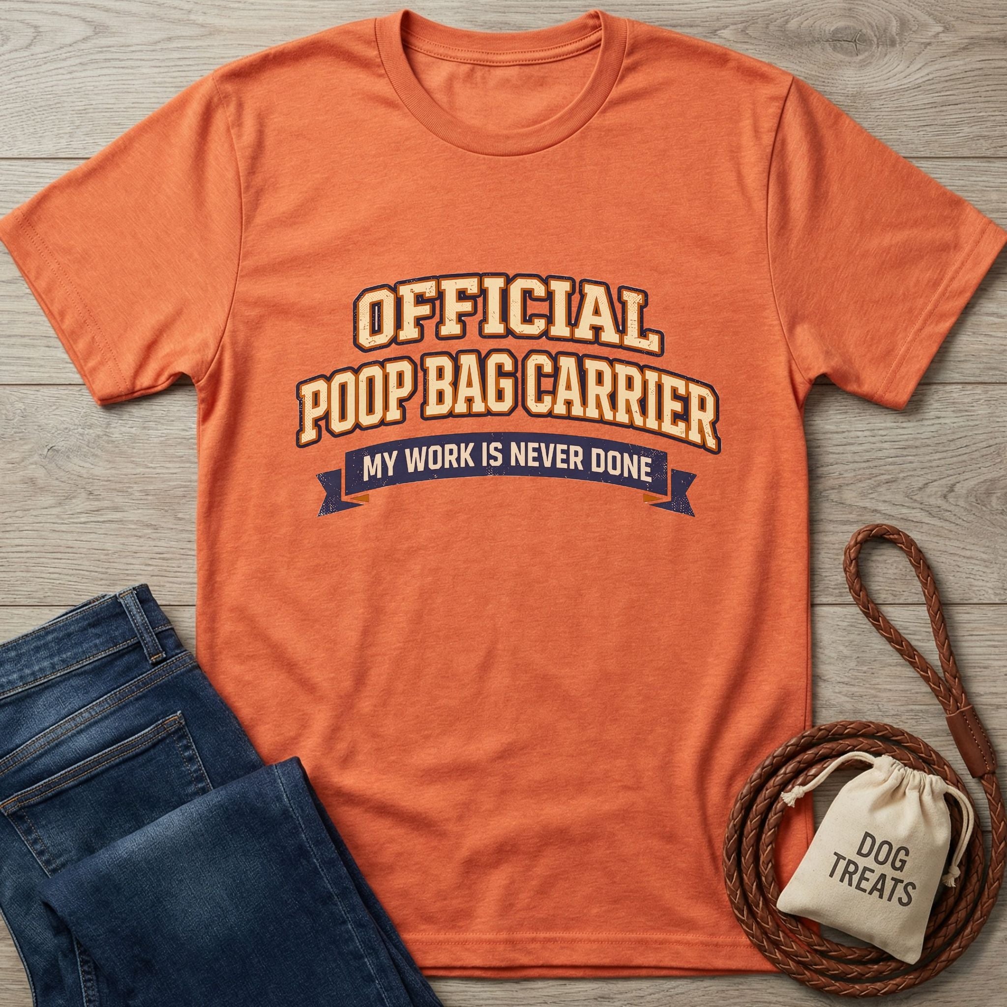 Orange Gildan Softstyle® t-shirt with "Official Poop Bag Carrier" text, next to jeans and dog treats.