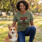 Woman in an olive green "Adopt Don't Shop" t-shirt with a noose design, kneeling with a Corgi.