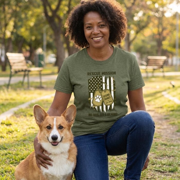 Woman in olive green "Rescue Mission" tee with American flag design and dog tags, kneeling with a Corgi.