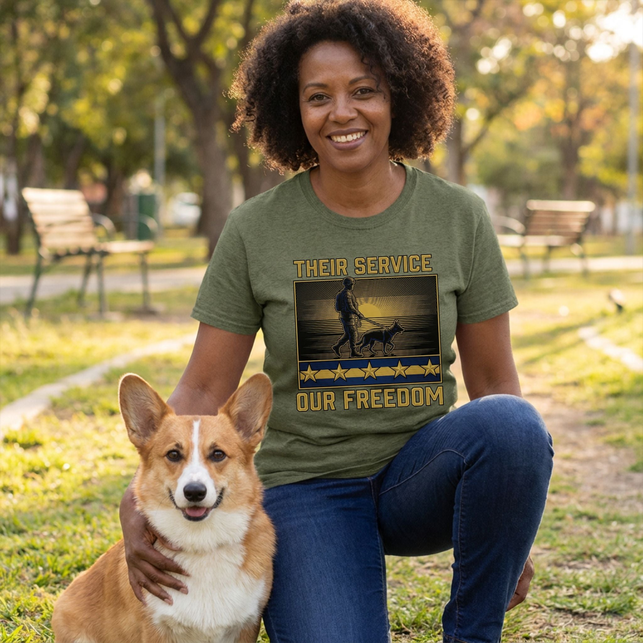 Woman in olive green "Their Service Our Freedom" t-shirt with a dog graphic, kneeling with a corgi.